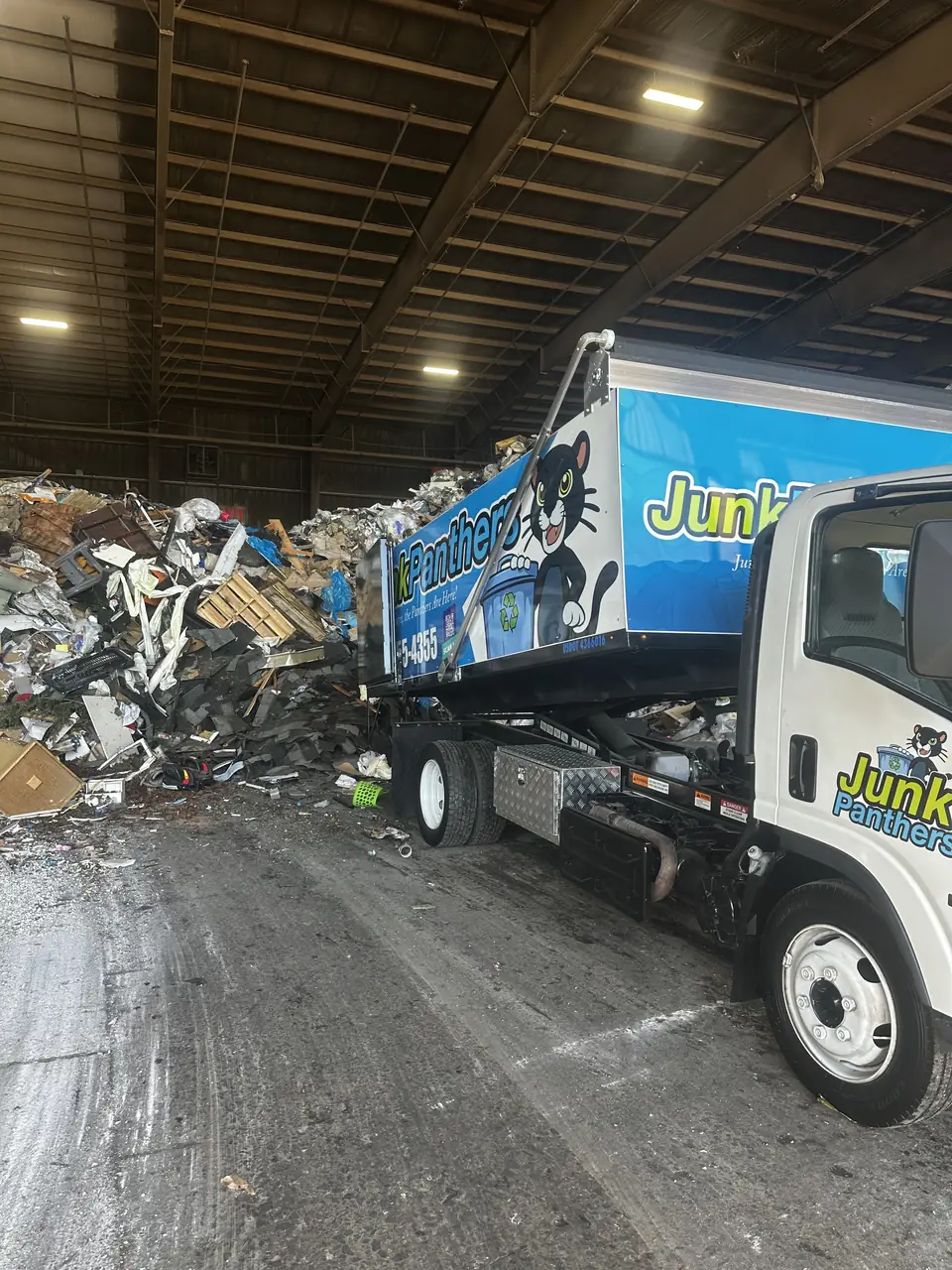 Junk Panthers truck unloading at a transfer station next to a pile of debris